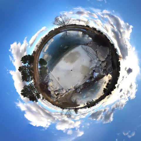 Snowy landscape wrapped into a little planet surrounded by blue sky